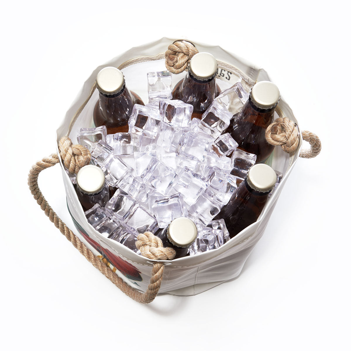 Six brown glass bottles in a white Key West Rooster Beverage Bucket from Sea Bags, filled with ice cubes and viewed from above. The bucket features rope handles on either side and is crafted from recycled sail cloth, offering a unique and eco-friendly touch. by Sea Bags