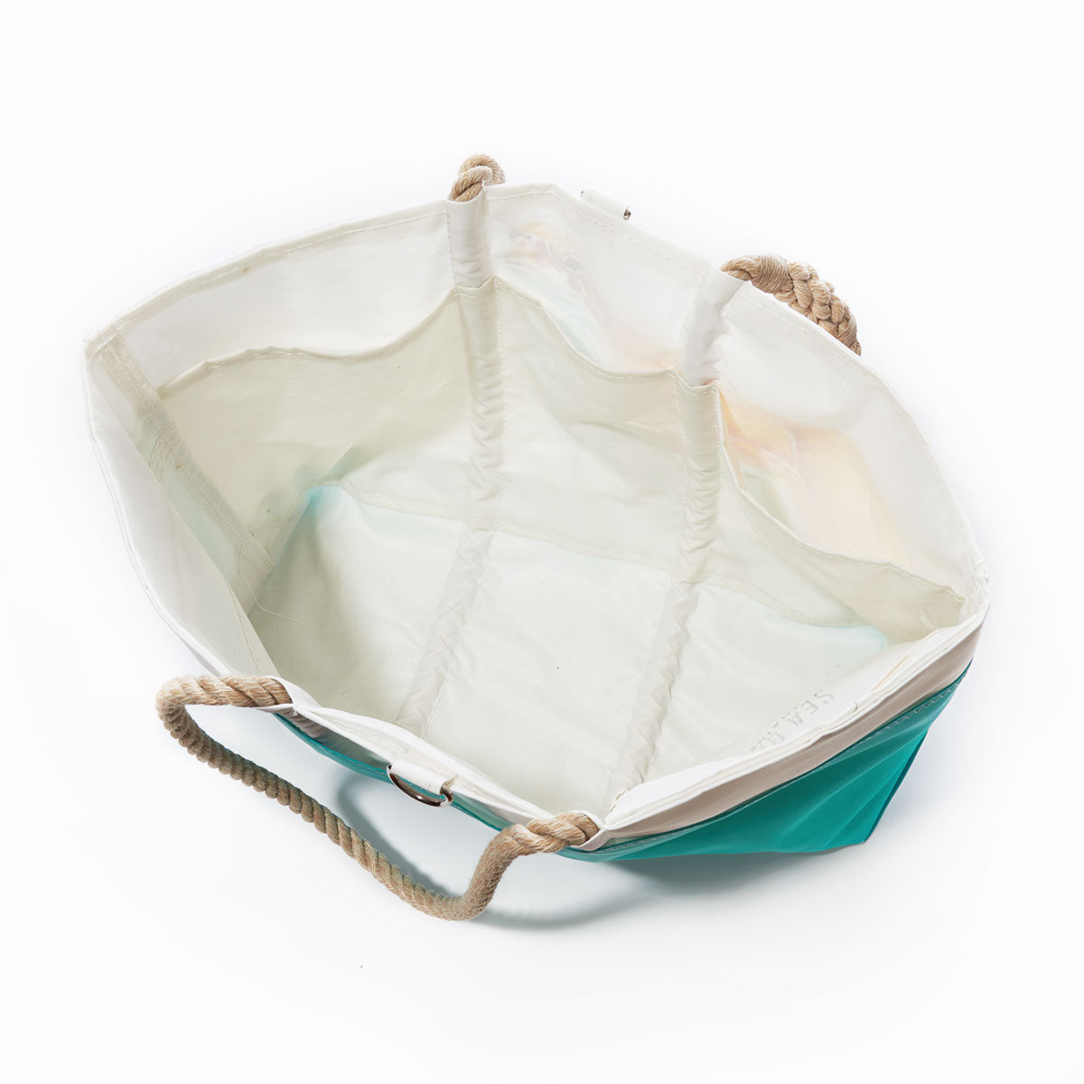 Open, empty Multicolor Sea Turtle Ogunquit Beach Tote by Sea Bags with a white interior, teal exterior, two rope handles, and visible stitching, viewed from above. by Sea Bags
