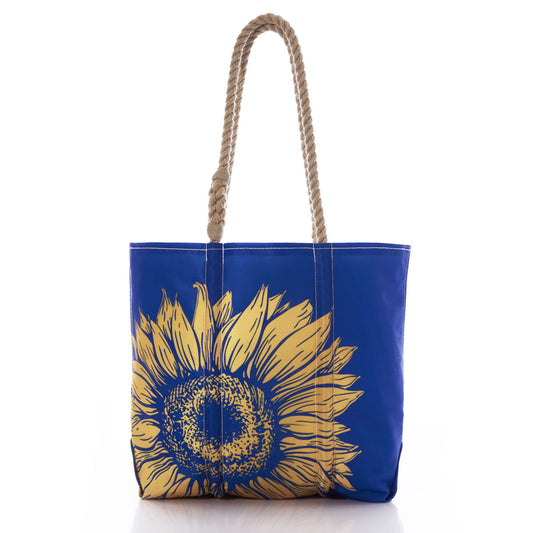 Sea Bags Sunflower Medium Tote—a blue tote featuring a large yellow sunflower design on the front and two twisted rope handles, displayed on a white background—makes the perfect bold floral accessory for any gardener. by Sea Bags