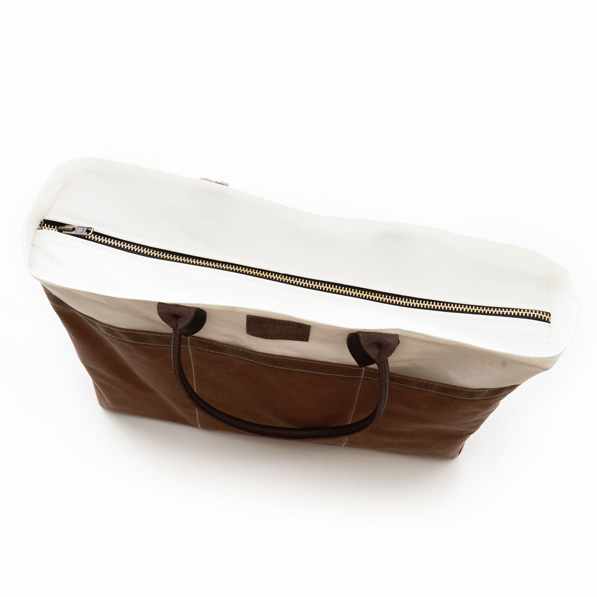 Introducing the Sea Bags Tan Chebeague Large Travel Tote—a spacious brown and white bag made from recycled sail cloth, featuring a zipper closure and two dark handles. Captured in a top-down view, this versatile travel tote is perfect for your next adventure. by Sea Bags