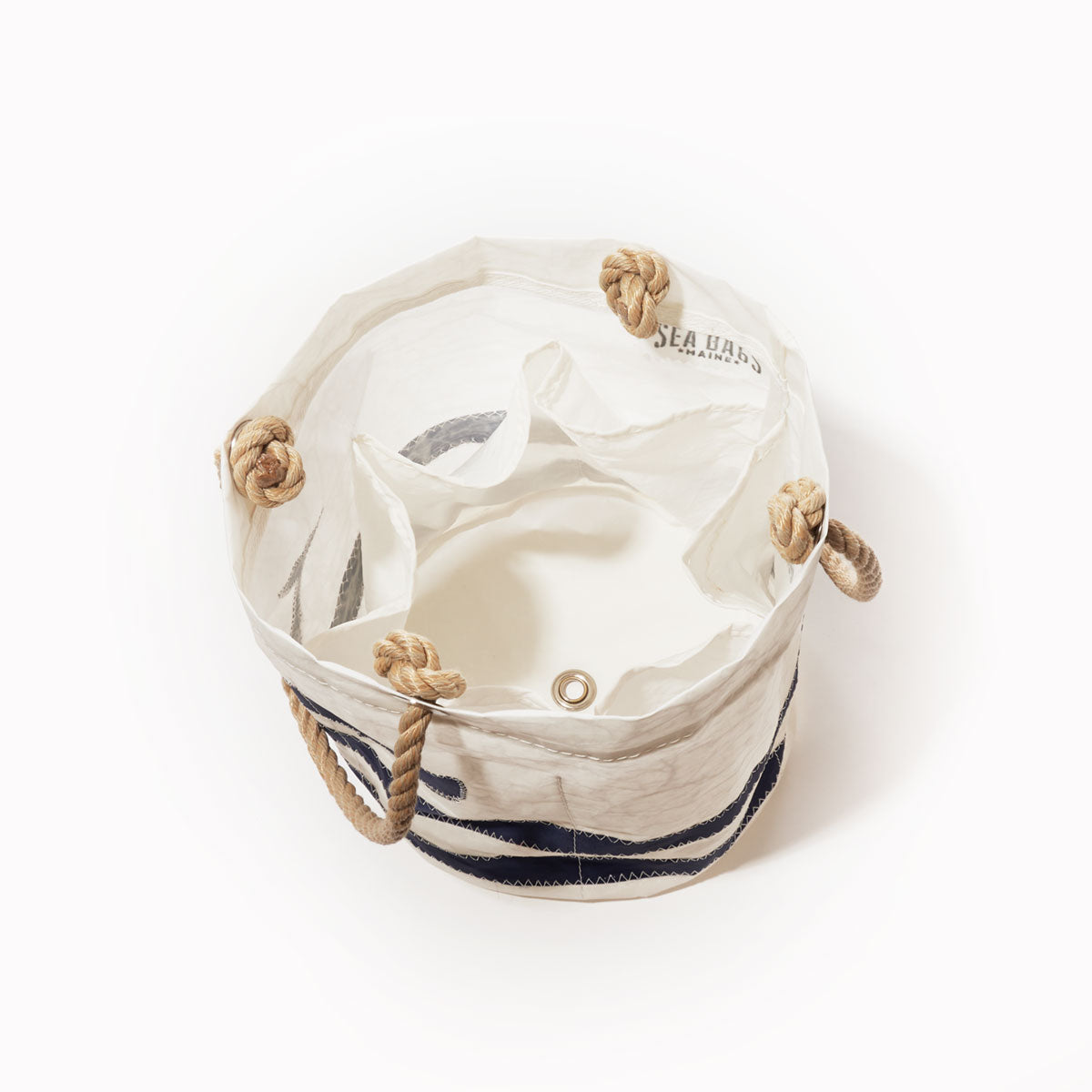 The Breton Stripe Whale Beverage Bucket from Sea Bags—a round canvas tote bag featuring rope handles, interior pockets, and a grommet hole with a nautical cooler-inspired design—is photographed from above on a white background. by Sea Bags