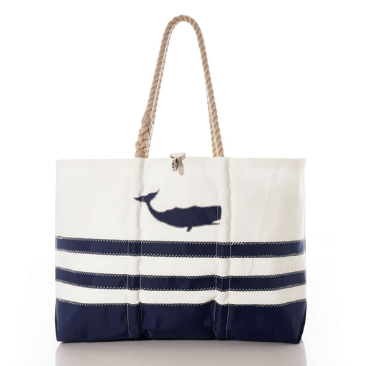 Sea Bags Breton Stripe Whale Ogunquit Beach Tote is crafted from eco-friendly recycled sail cloth and features rope handles, a striped bottom section in white and navy, and a whale silhouette design on the upper front. by Sea Bags