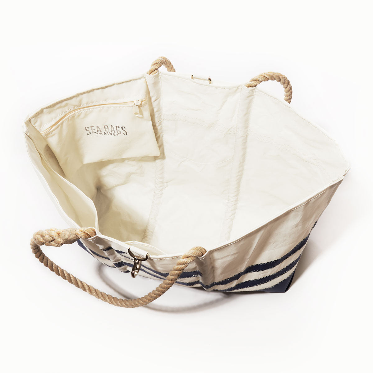 Introducing the Breton Stripe Whale Ogunquit Beach Tote by Sea Bags—a spacious white canvas tote featuring classic blue stripes, sturdy rope handles, and an interior pocket adorned with the Sea Bags label. Crafted from recycled sail cloth, this eco-friendly beach bag combines nautical style with sustainability, making it ideal for all your coastal adventures. by Sea Bags