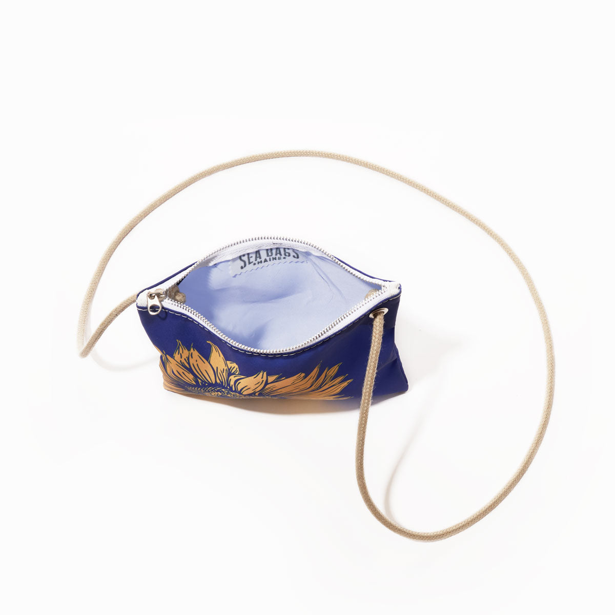 The Sunflower Slim Crossbody by Sea Bags is a small blue zippered bag with a beige strap and a visible “Sea Bags” label inside, designed for nature lovers and photographed against a white background. by Sea Bags