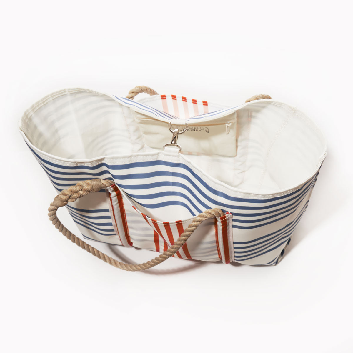 The Sea Bags Picnic Stripe Pier Tote is a large weatherproof beach bag featuring blue and red stripes, beige rope handles, a white interior, and a small attached pocket. The tote is shown empty and viewed from above. by Sea Bags