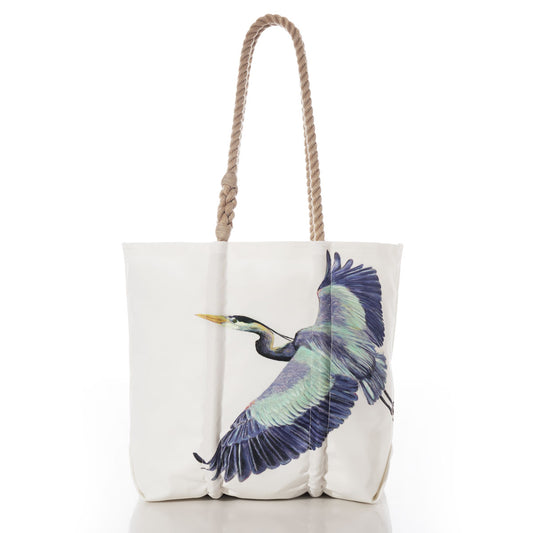 Introducing the Great Blue Heron Medium Tote by Sea Bags—a stylish white canvas tote bag crafted from recycled sail cloth. This eco-friendly accessory features thick rope handles and a striking graphic print of a blue heron in flight on the front, set against a crisp white background. Perfect for nature lovers, it combines sustainable materials with eye-catching design. by Sea Bags