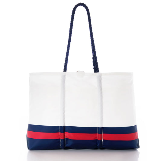 The New England Patriots Tailgate Tote by Sea Bags is a white tote bag crafted from recycled sail cloth, featuring navy blue and red horizontal stripes near the base and sturdy navy blue rope handles. Displayed on a white background, this durable and versatile accessory combines nautical style with eco-friendly materials. by Sea Bags