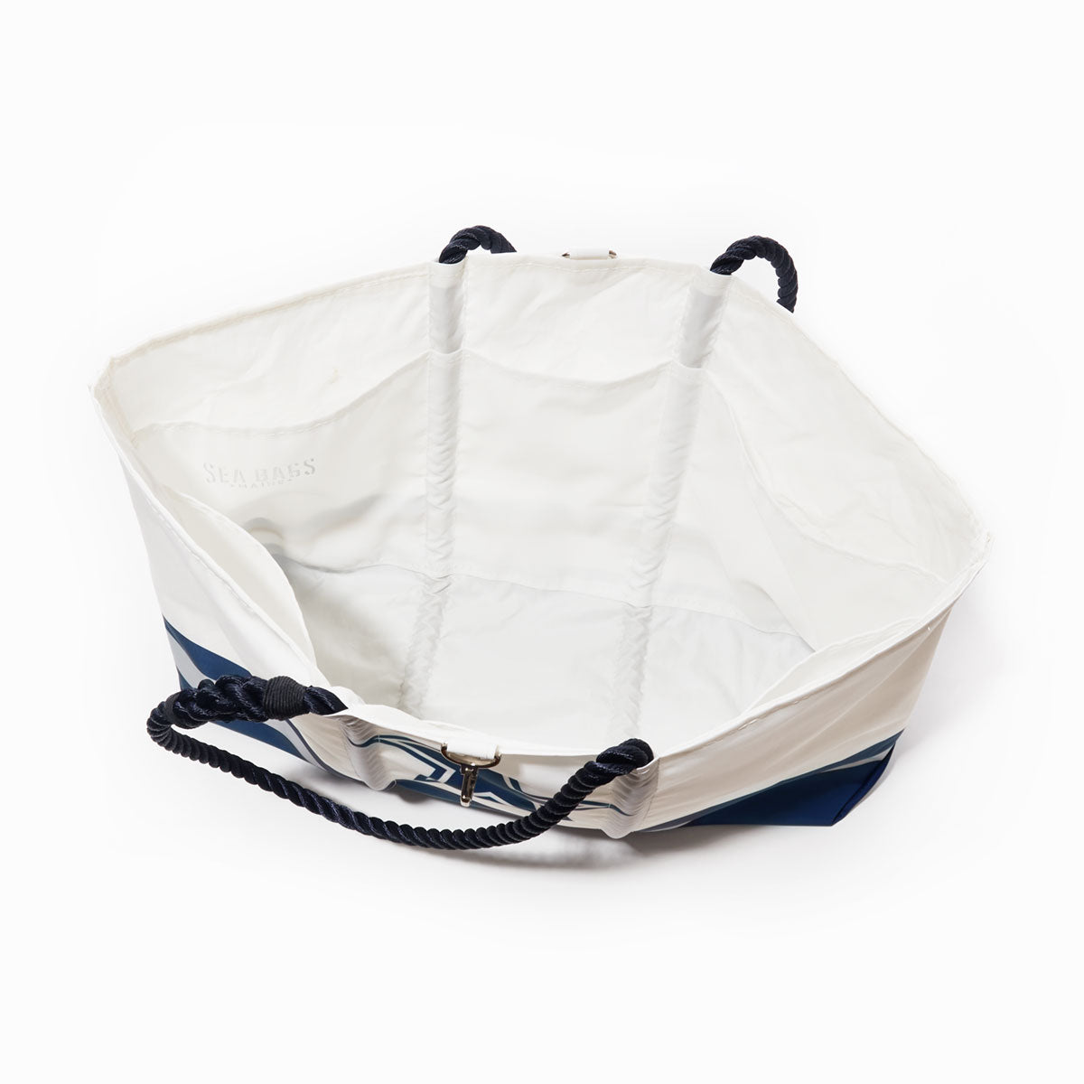 The Sea Bags Dallas Cowboys Tailgate Tote—a large, white and blue tote bag with black rope handles—is pictured from above, revealing its spacious, empty interior against a white background. Expertly crafted from recycled sail cloth, this stylish and durable accessory is the perfect choice for football fans. by Sea Bags