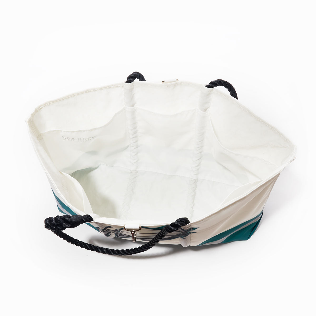 The Philadelphia Eagles Tailgate Tote by Sea Bags is a large open tote bag made from recycled sail cloth, showcasing teal accents on the exterior, black rope handles, and a white interior—ideal for football tailgates. Photographed from above against a white background. by Sea Bags