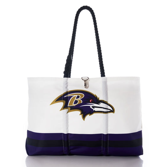 The Baltimore Ravens Tailgate Tote by Sea Bags features a white design with black handles, the Baltimore Ravens logo, and bold purple and black stripes near the bottom. Crafted from recycled sail cloth for enhanced durability, this stylish tote is ideal for both game days and everyday use. by Sea Bags