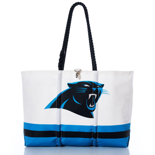The Carolina Panthers Tailgate Tote by Sea Bags is a white tote bag with black handles, prominently displaying the teams logo and bold blue and black stripes near the bottom. Photographed against a white background, this stylish eco-friendly tote is crafted from recycled sail cloth—perfect for fans looking for a unique NFL logo accessory. by Sea Bags