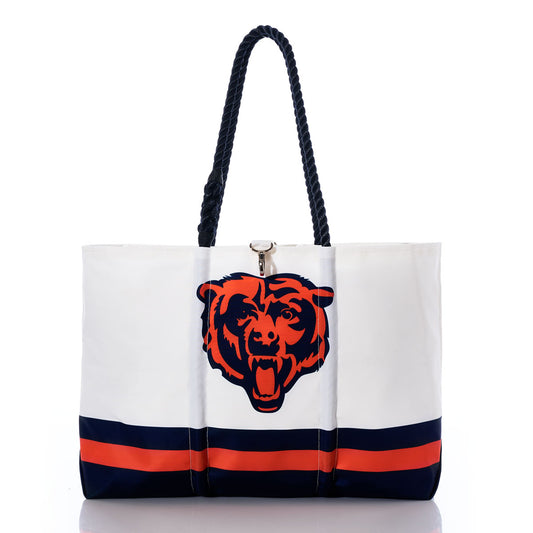 The Chicago Bears Tailgate Tote by Sea Bags is crafted from recycled sail cloth, making it both eco-friendly and durable. This white tote features navy blue and orange stripes, a striking graphic of a roaring bears head, and black braided handles—the perfect choice for any NFL logo bag enthusiast. by Sea Bags