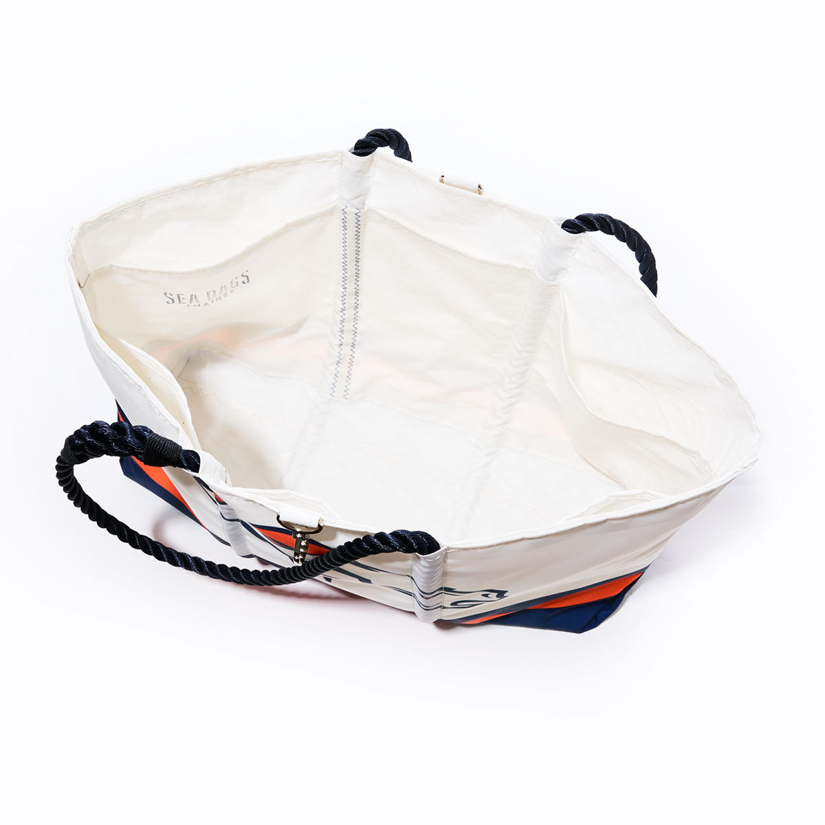 Denver Broncos Tailgate Tote by Sea Bags, crafted from recycled sail cloth with dark rope handles, open to reveal its spacious interior, labeled Sea Bags inside near the top edge, resting on a white surface. by Sea Bags