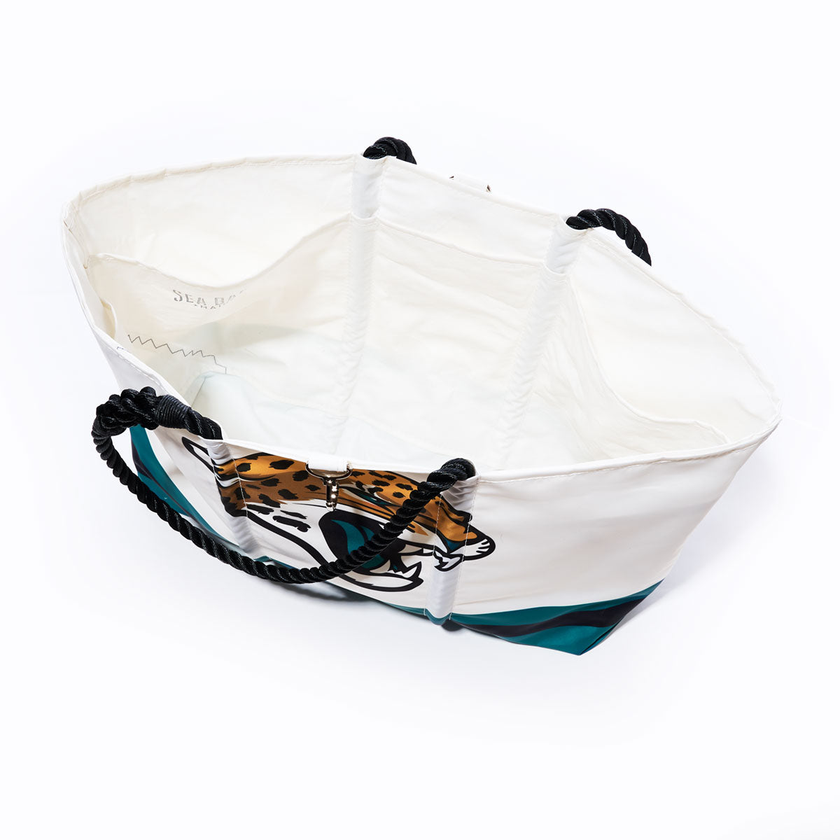 Introducing the Sea Bags Jacksonville Jaguars Tailgate Tote: a spacious white tote bag crafted from recycled sail cloth, featuring bold black rope handles and an eye-catching jaguar graphic on the exterior. With its open-top design and roomy white interior, this NFL logo bag combines sporty style and eco-friendly materials—perfect for Jaguars fans who value fashion and sustainability. by Sea Bags
