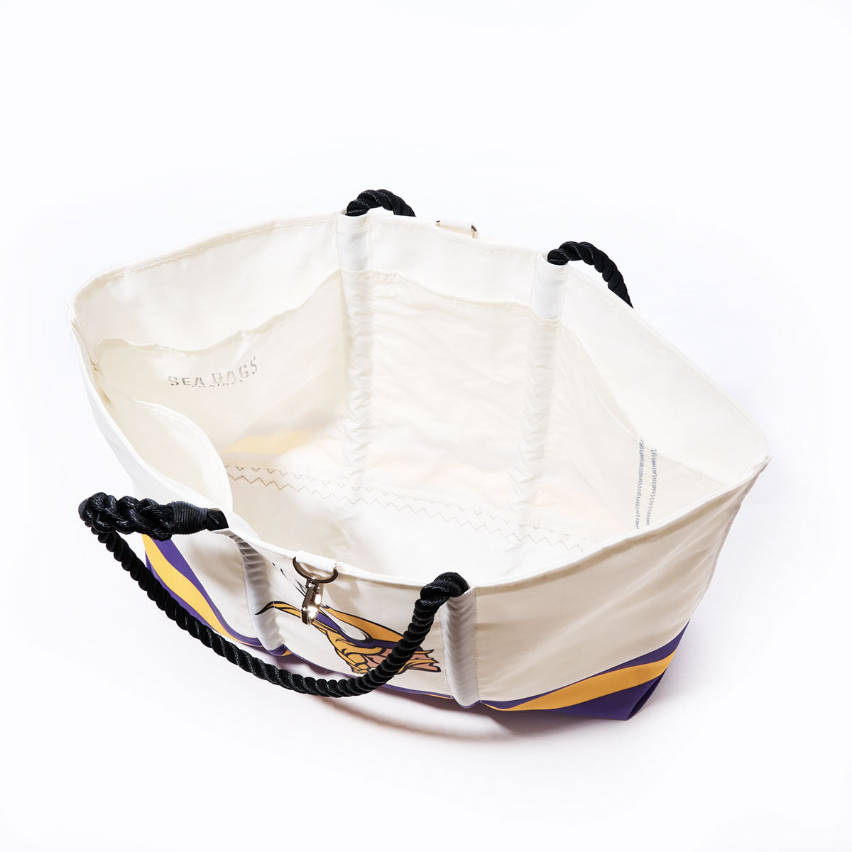 Sea Bags Minnesota Vikings Tailgate Tote—crafted from recycled sail cloth and featuring sturdy black rope handles, gold hardware, and a striking purple and yellow design on the front. Perfect for any Vikings fan, this tote is pictured empty from above against a white background. by Sea Bags
