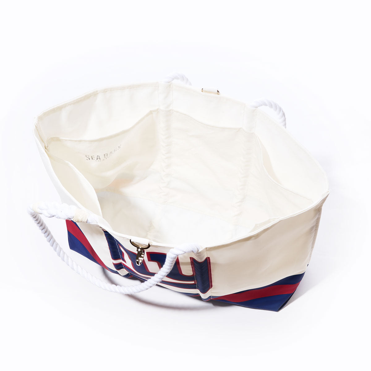 Photographed from above on a white background, the New York Giants Tailgate Tote by Sea Bags is an open white canvas tote bag crafted from recycled sail cloth, featuring striking red and blue stripes on the exterior and rope handles—a stylish and sustainable choice for any tailgate event. by Sea Bags