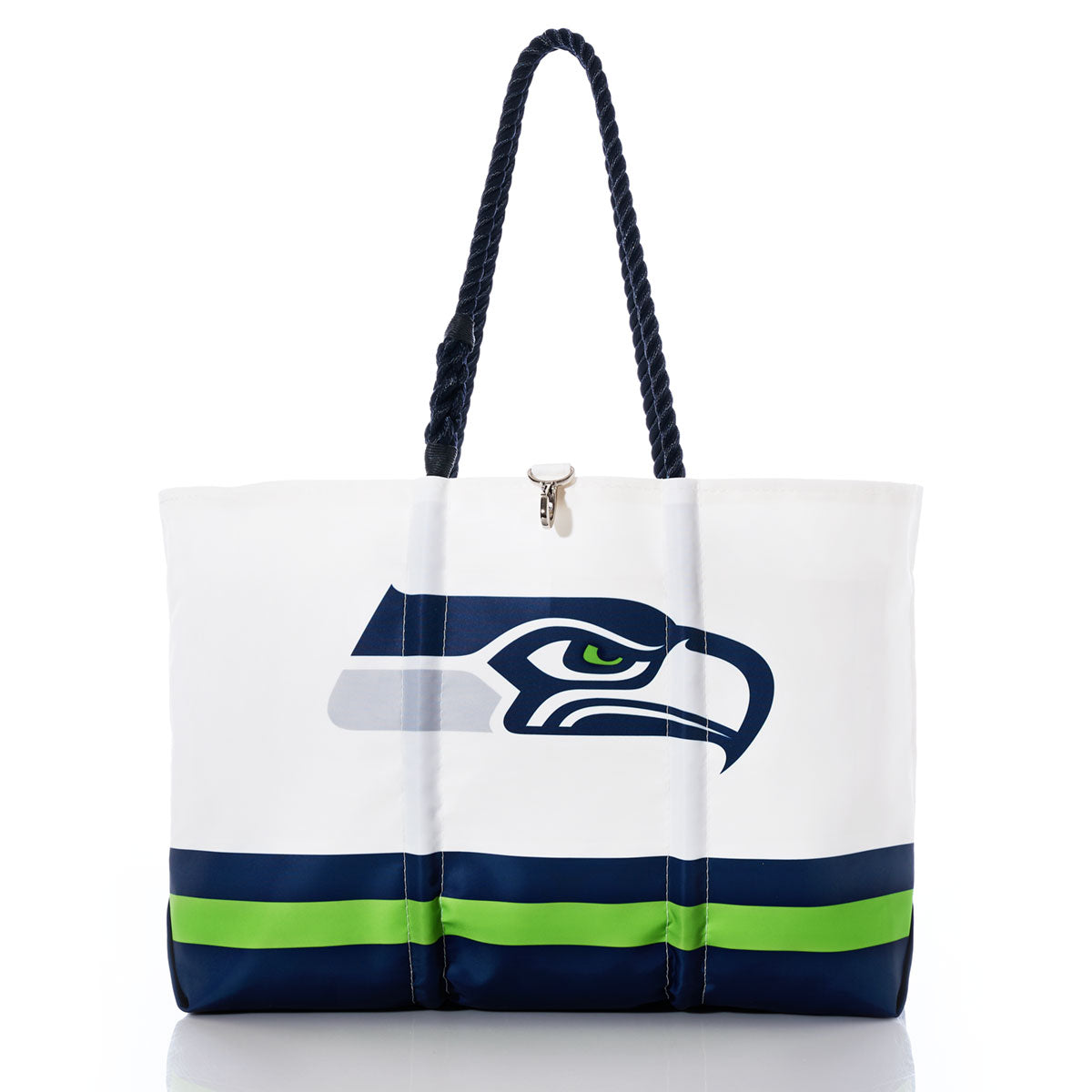 Introducing the Seattle Seahawks Tailgate Tote by Sea Bags—a white tote crafted from recycled sail cloth, featuring sturdy navy blue rope handles, the official Seahawks logo, and bold blue and green stripes at the bottom. This eco-friendly NFL bag is a stylish and sustainable choice for any Seattle fan. by Sea Bags