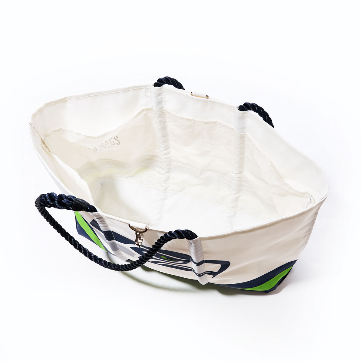 The Sea Bags Seattle Seahawks Tailgate Tote is a large white bag made from recycled sail cloth, featuring navy blue rope handles and an abstract green and blue design. Shown open and empty against a white background. by Sea Bags