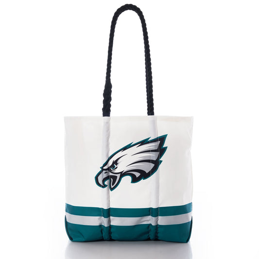 Introducing the Philadelphia Eagles Medium Tote by Sea Bags—a white tote bag with black handles, featuring a teal and black eagle head logo and two horizontal teal stripes near the bottom. Made from recycled sail cloth, this eco-friendly and stylish accessory is the perfect gift for any Philadelphia Eagles fan. by Sea Bags
