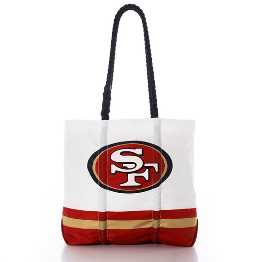 Show your San Francisco 49ers pride with the Sea Bags San Francisco 49ers Medium Tote. This eco-friendly tote features bold red and gold stripes near the bottom, black handles, and the teams logo on a white background. Crafted from recycled sail cloth, it’s a durable and stylish choice for fans looking to support their team while making a sustainable statement. by Sea Bags