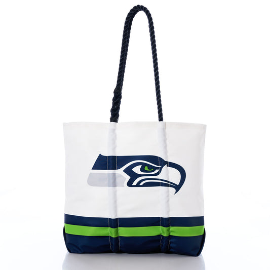 The Sea Bags Seattle Seahawks Medium Tote is crafted from white recycled sail cloth with dark blue handles, featuring the Seattle Seahawks logo along with green and blue stripes near the bottom. Shown on a white background, this stylish tote bag is perfect for any fan. by Sea Bags