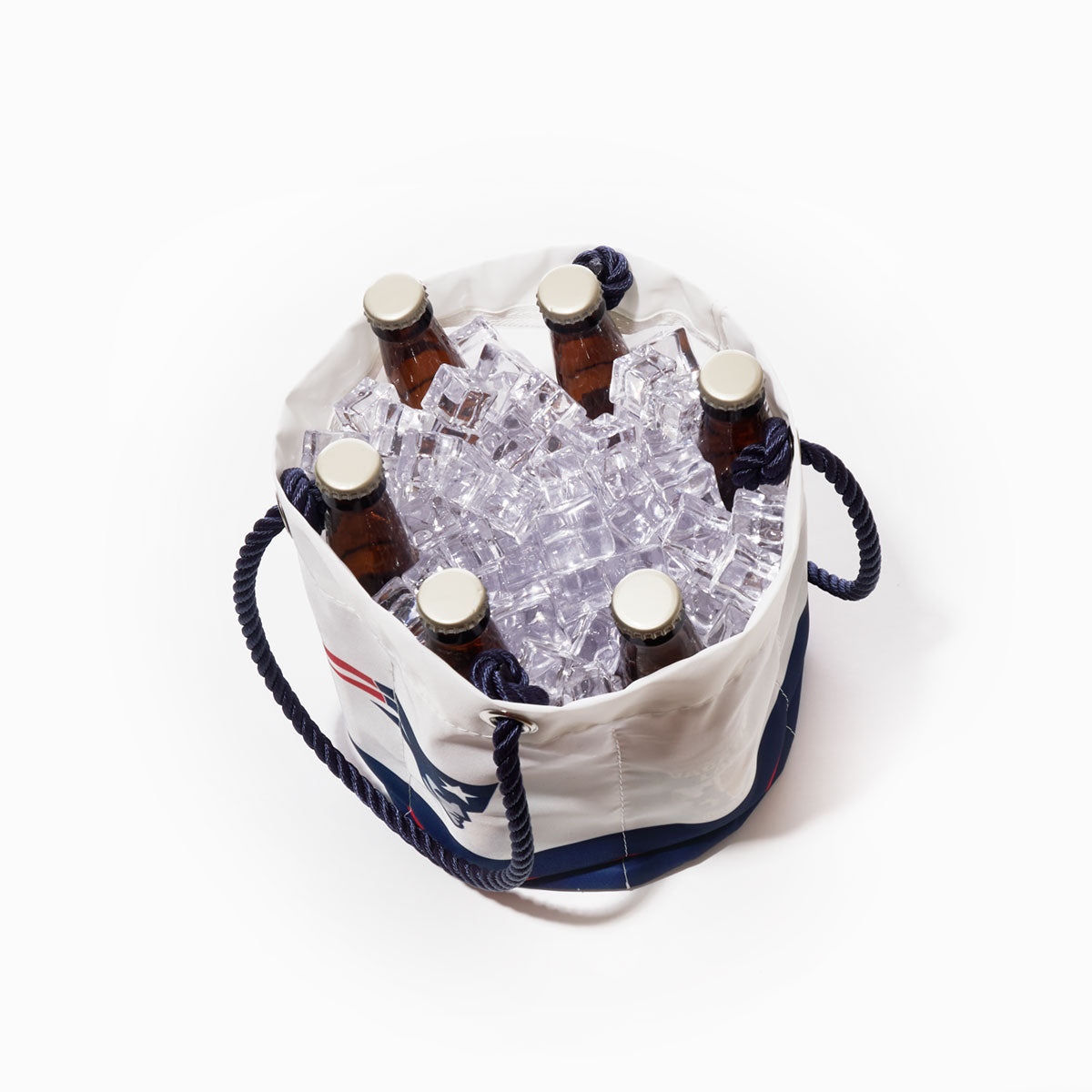 Six brown glass bottles with caps are placed upright in a Sea Bags New England Patriots Beverage Bucket filled with ice cubes, featuring dark rope handles on either side, set against a white background. by Sea Bags