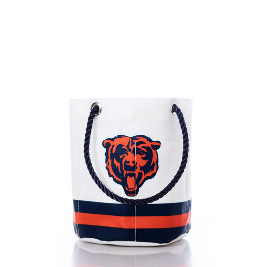 The Sea Bags Chicago Bears Beverage Bucket is a white recycled sail cloth bucket bag with blue rope handles, adorned with a roaring bear logo and horizontal navy and orange stripes near the base—making it the perfect sustainable cooler for showcasing your Chicago Bears pride. by Sea Bags