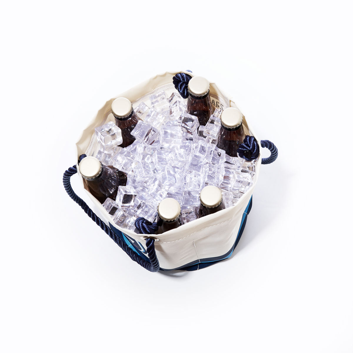 A top-down view of six capped glass bottles in the Tennessee Titans Beverage Bucket by Sea Bags, a white and blue sustainable cooler made from recycled sail cloth, filled with ice cubes. by Sea Bags