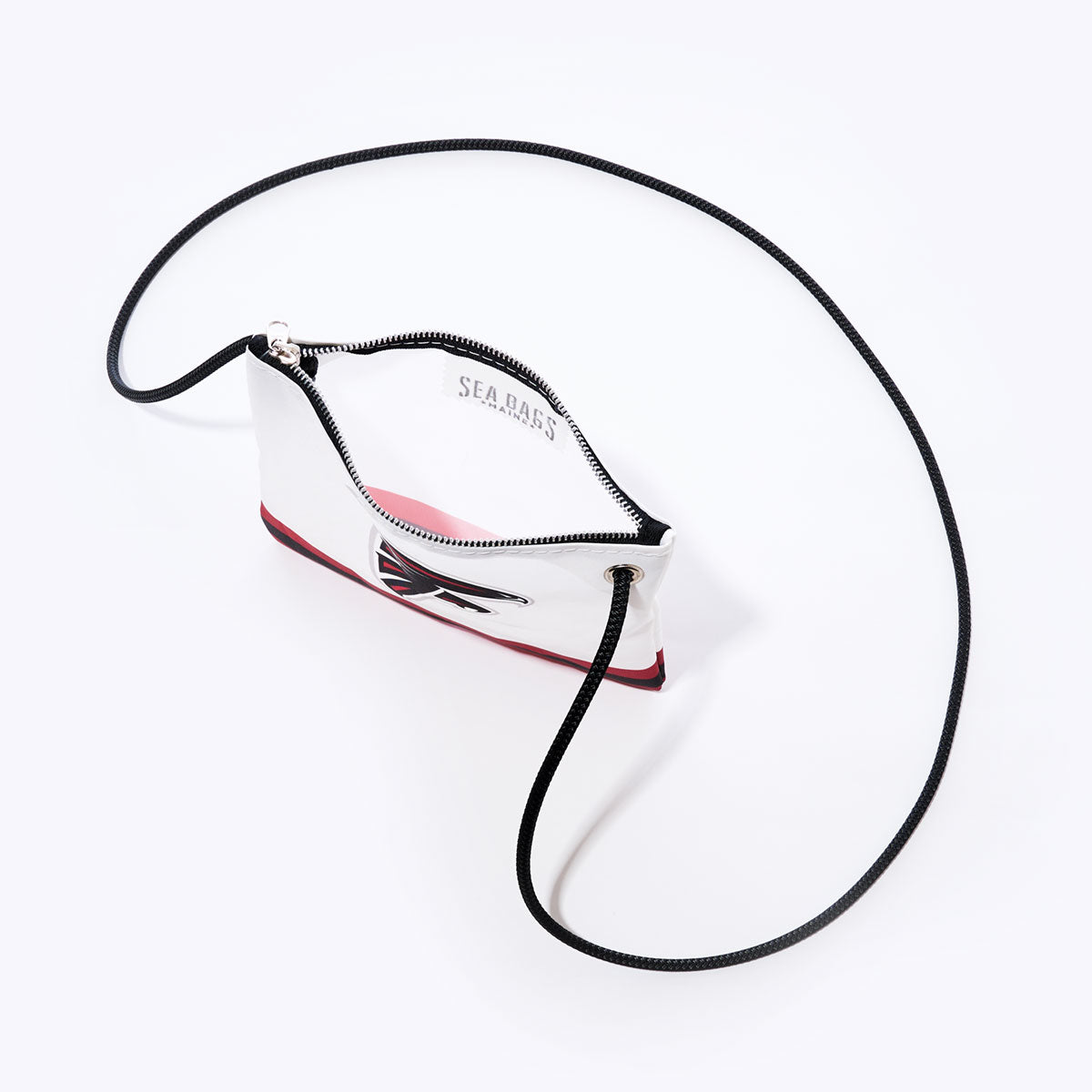 The Atlanta Falcons Slim Crossbody from Sea Bags is a white pouch crafted from recycled sail cloth, featuring a black rope strap, a zippered top opening, and an Atlanta Falcons-themed graphic—perfect for fans looking for an eco-friendly accessory. by Sea Bags