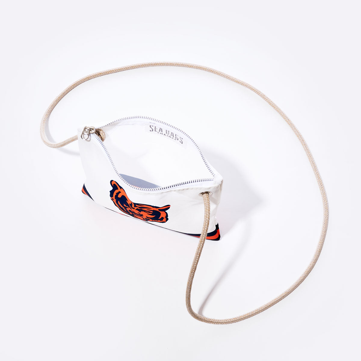 The Chicago Bears Slim Crossbody by Sea Bags is a small white zippered pouch made from recycled sail cloth, featuring a blue and orange graphic inspired by the Chicago Bears, a beige rope strap, and “SEABASS” printed inside—all set against a plain white background. by Sea Bags