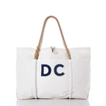Sea Bags Custom Monogram Wharf Tote—crafted from rugged sail cloth, this white tote features sturdy rope handles, a convenient front pocket, and bold dark blue custom monogram letters on the front. Displayed against a white background, it’s the perfect personalized sail bag or classic Sea Bags tote. by Sea Bags