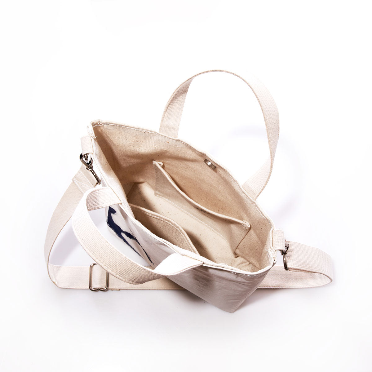 Navy Anchor Crossbody Tote by Sea Bags, crafted from recycled sailcloth, features white straps, interior pockets, and a spacious main compartment; shown open and photographed from above on a white background. by Sea Bags
