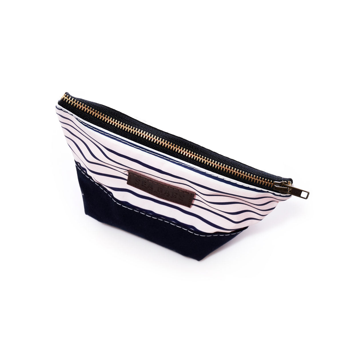 The Sea Bags Navy Mariner Stripe Chebeague Cosmetic Bag is a small zippered pouch crafted from recycled sailcloth, featuring a navy bottom, a white top with black wavy lines, canvas and leather accents, and a brown side label. by Sea Bags