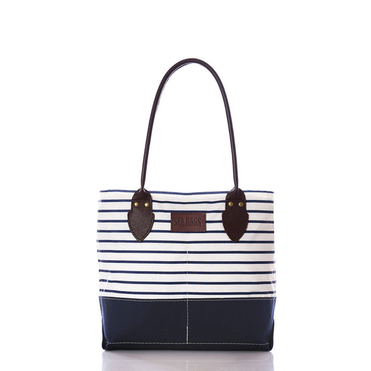 The Sea Bags Navy Mariner Stripe Chebeague Handbag features navy and white stripes, dark handles, and a brown leather patch on the front. Handmade from recycled sail cloth on Chebeague Island, it is shown against a white background. by Sea Bags