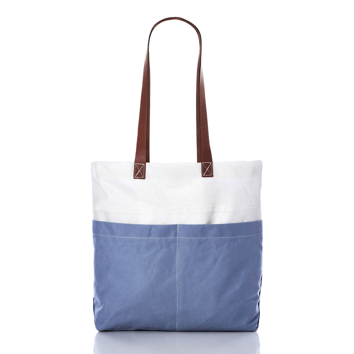 The Sea Bags Chambray Blue Chebeague Market Tote, crafted from recycled sails, showcases a two-tone design with a white upper section, chambray blue lower section, and durable brown leather handles, displayed against a white background. by Sea Bags