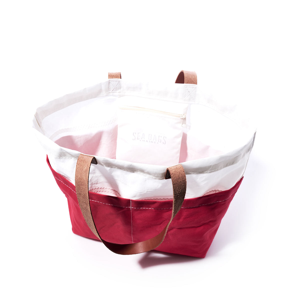 The Sea Bags Red Chebeague Market Tote, made from recycled sails and featuring brown leather handles, is shown on a white background. by Sea Bags