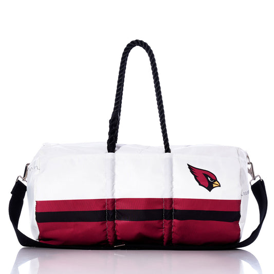 The Sea Bags Arizona Cardinals Duffel, made from recycled sail cloth, features sturdy black handles, a bold red and black horizontal stripe, and a cardinal bird logo on the side. Photographed against a white background, this durable bag showcases NFL team pride with eco-friendly style. by Sea Bags