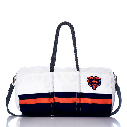 The Chicago Bears Duffel by Sea Bags is a white duffel bag made from recycled sail cloth, featuring black rope handles, navy and orange stripes, and a bear head logo on the right side—an ideal accessory for NFL fans. by Sea Bags