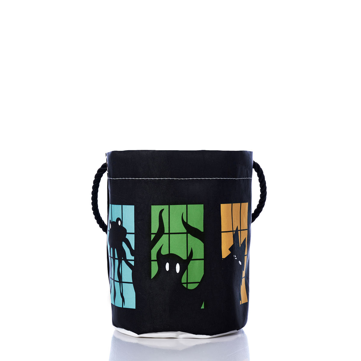 The Sea Bags Monster Party Bucket Bag is decorated with silhouettes of monsters in blue, green, and orange window panels against a white background. Featuring durable rope handles, this eco-friendly Halloween bucket bag is crafted from recycled sails, making it both festive and sustainable.