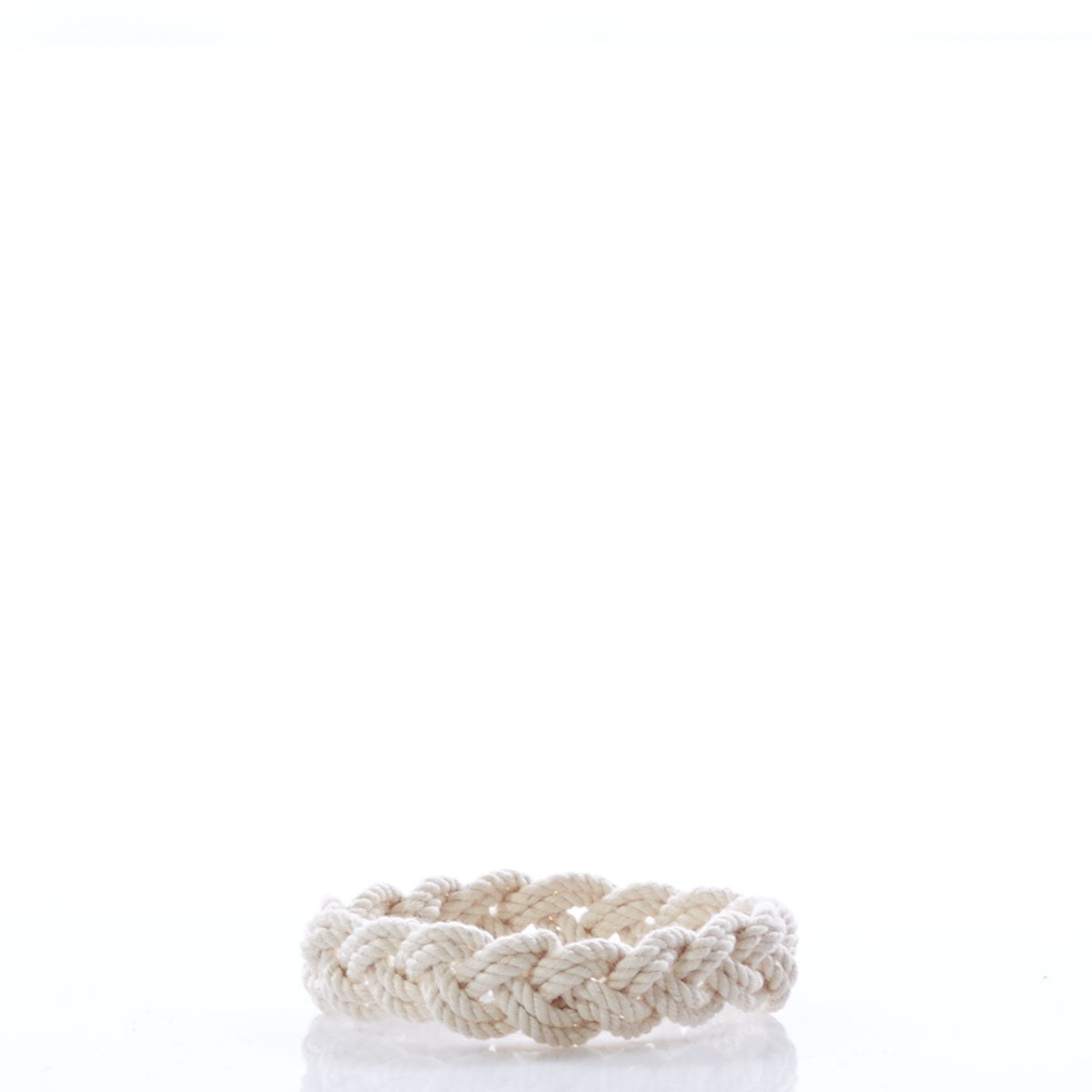 A braided natural rope, the Nantucket Knotworks Bracelet by Nantucket Knotworks, is arranged in a circular shape and sits on a white reflective surface with a plain white background. by Sea Bags