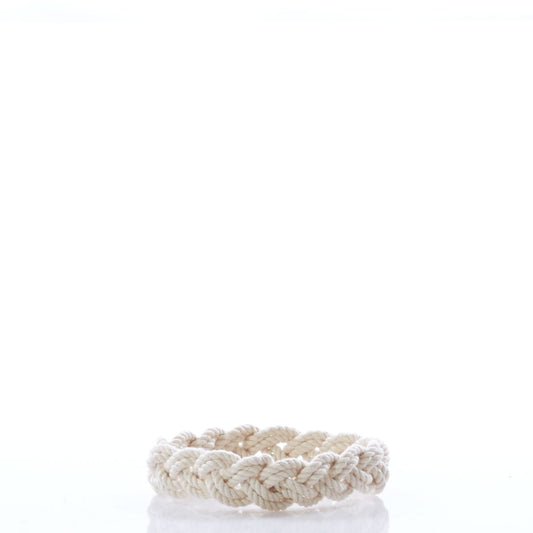 A braided natural rope, the Nantucket Knotworks Bracelet by Nantucket Knotworks, is arranged in a circular shape and sits on a white reflective surface with a plain white background. by Sea Bags