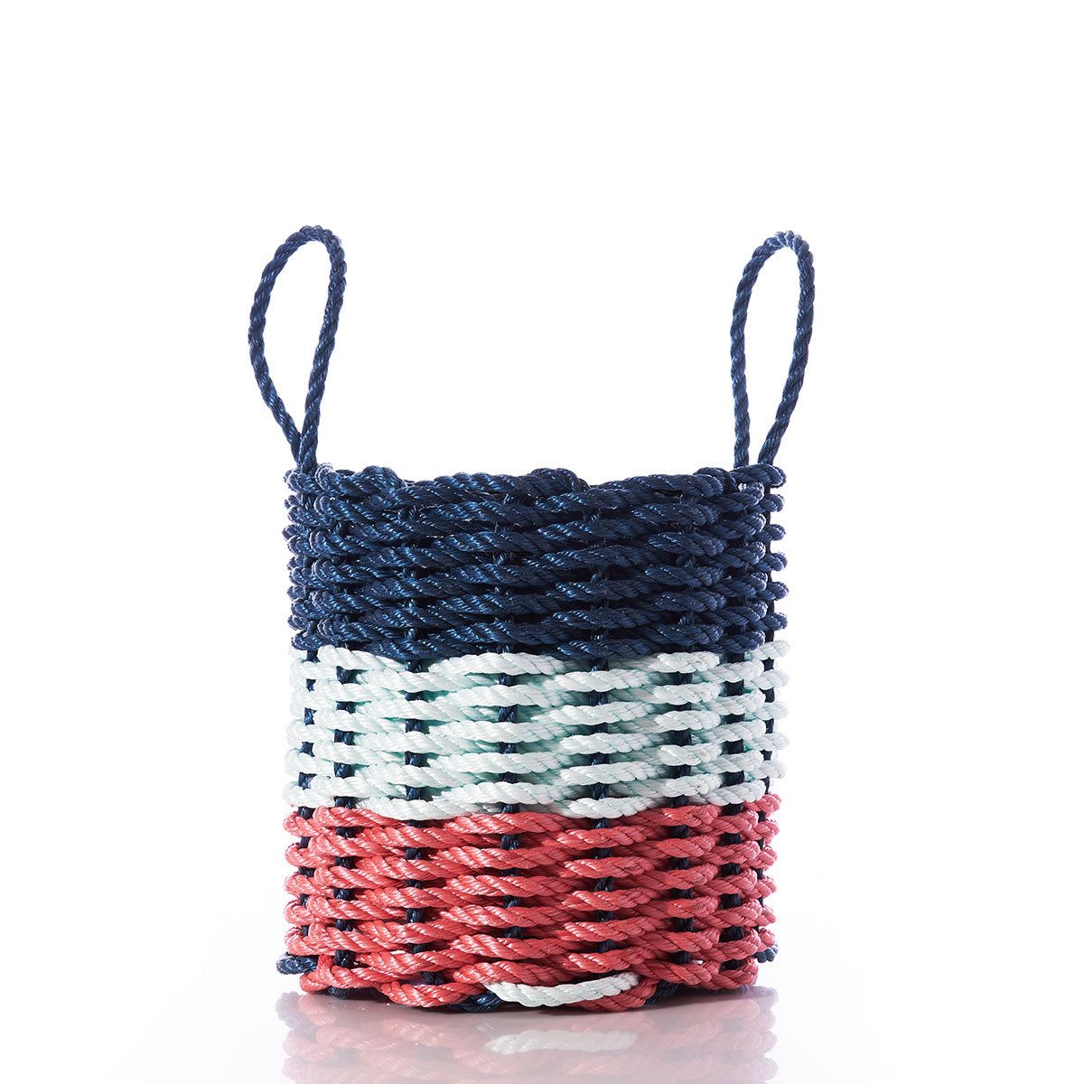 A Fisherman Rope Basket with two handles from Custom Cordage / DBA Maine Rope Mats, featuring horizontal sections in navy, sea foam, and red, photographed on a white background. Inspired by traditional Maine craftsmanship, the Fisherman Rope Basket - Navy, Sea Foam,  Red is an eco-friendly choice for stylish storage. by Sea Bags