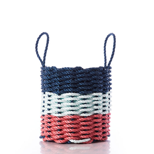 A Fisherman Rope Basket with two handles from Custom Cordage / DBA Maine Rope Mats, featuring horizontal sections in navy, sea foam, and red, photographed on a white background. Inspired by traditional Maine craftsmanship, the Fisherman Rope Basket - Navy, Sea Foam,  Red is an eco-friendly choice for stylish storage. by Sea Bags