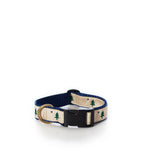 The Belted Cow Maine Flag Dog Collar 1 - Medium features a beige nylon webbing adorned with green tree and star motifs, a sturdy black plastic buckle, navy blue lining, and a durable metal D-ring. Proudly made in the USA, this stylish collar is showcased against a white background. by Sea Bags