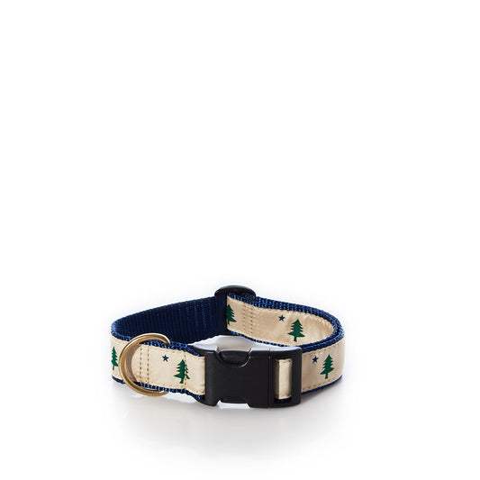 The Belted Cow Maine Flag Dog Collar 1 - Medium features a beige nylon webbing adorned with green tree and star motifs, a sturdy black plastic buckle, navy blue lining, and a durable metal D-ring. Proudly made in the USA, this stylish collar is showcased against a white background. by Sea Bags
