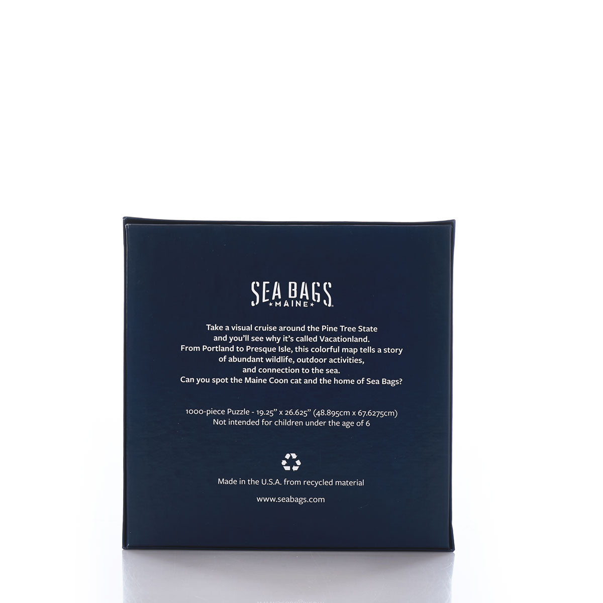 Galleyware’s Maine Landmarks Jigsaw Puzzle features a navy blue box with white text that highlights its Maine-themed map design, total piece count, recycled material usage, and manufacturing details. by Sea Bags