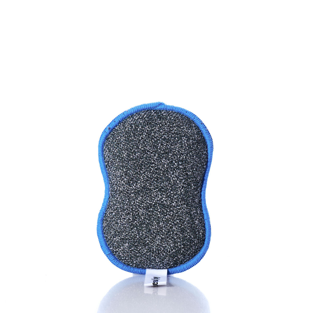 The Kate Nelligan Full Sail Dish Sponge by Once Again Home is a gray, textured cleaning sponge with blue edging, shown standing upright on a white background and crafted from recycled materials for a more sustainable home textiles solution. by Sea Bags