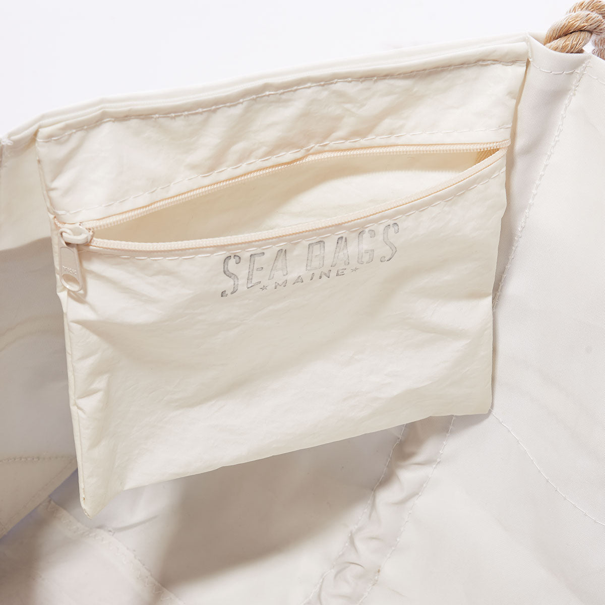 The interior of the Sea Bags Vintage Ideal 18 Medium Tote features a zippered pocket with SEA BAGS MAINE printed on it, and sturdy, hand-spliced rope handles at the top. An original sail insignia gives this one-of-a-kind accessory a distinctive touch. by Sea Bags